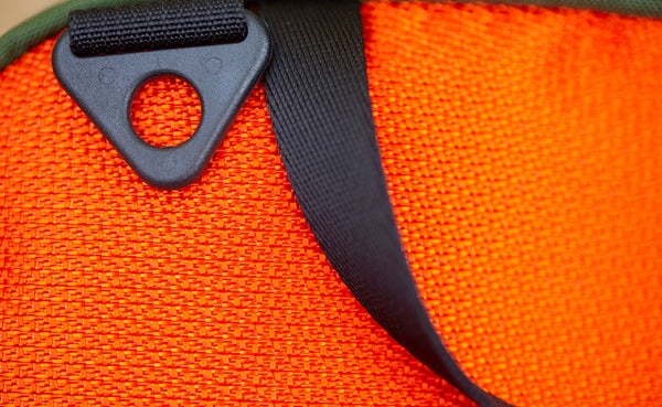 A close up picture of a Texturized Orange Grab Bag showing the d-ring shoulder strap attachment and grab handle.